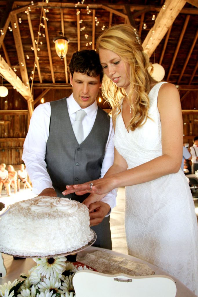 Bride and groom cut wedding cake at barn wedding venue Blodgett Wedding Barn in Schoolcraft, Michigan